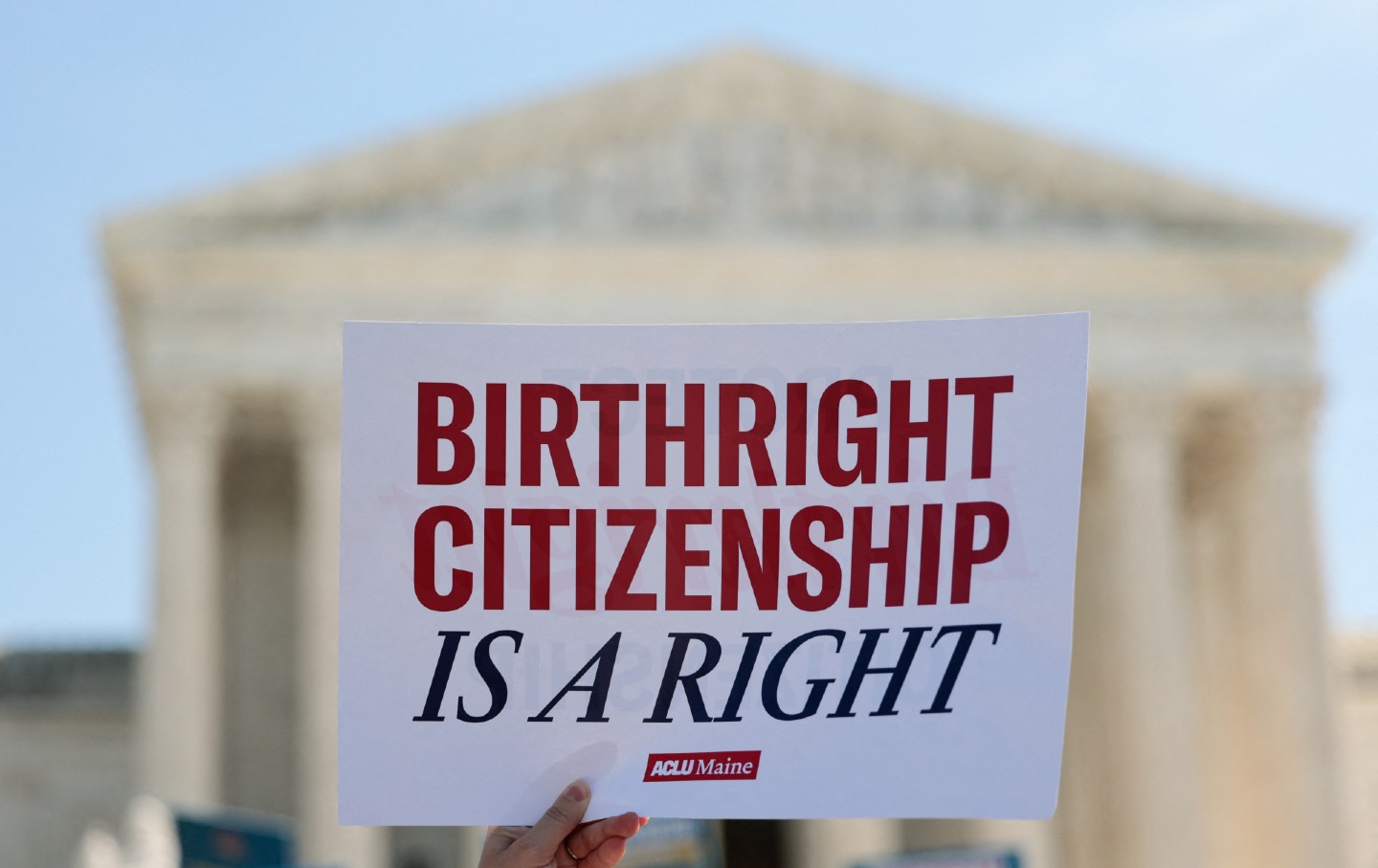 Uma pessoa segura um cartaz com a frase “Birthright Citizenship Is a Right” (“Cidadania por Nascimento é um Direito”) em frente ao prédio da Suprema Corte dos Estados Unidos