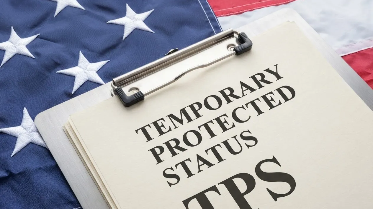 Document reading 'TEMPORARY PROTECTED STATUS TPS' attached to a clipboard over an American flag background.